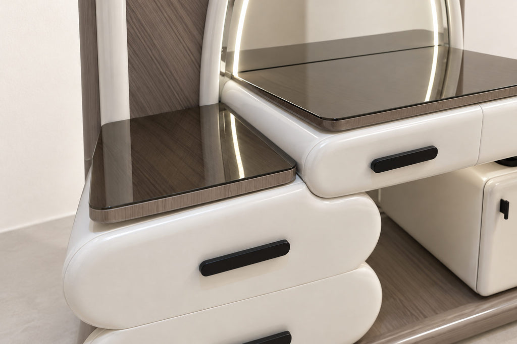 A close-up of a modern vanity or dressing table with white curved drawer fronts, dark wood-look surfaces, and black handles, shown in a clean interior setting.