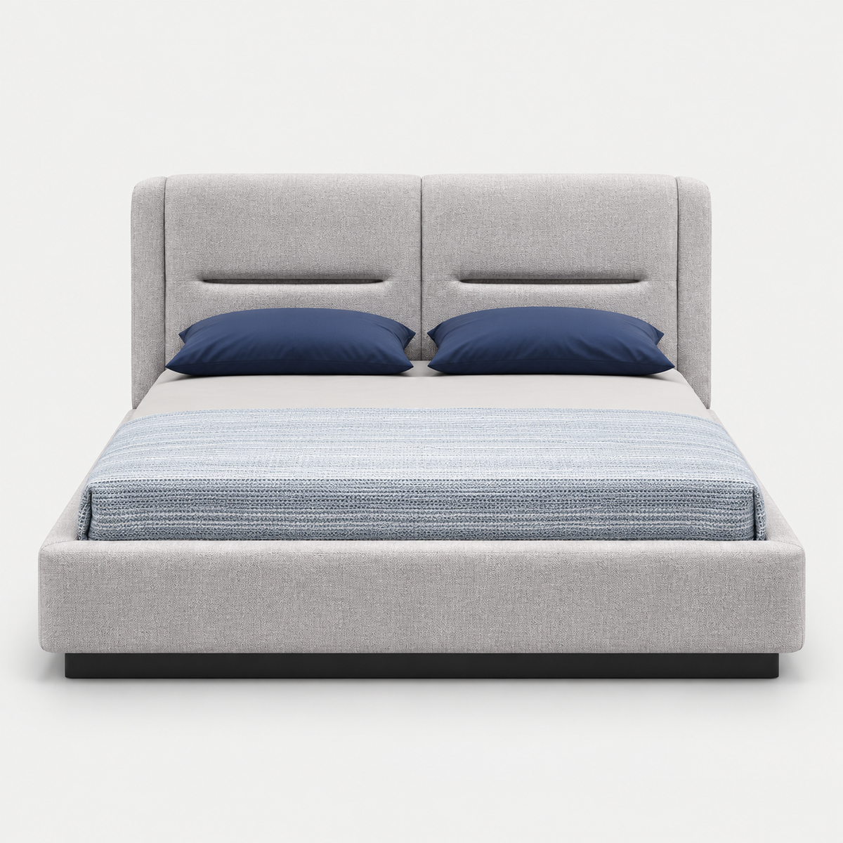 A modern platform bed with a light gray upholstered frame and tall segmented headboard, styled with two navy blue pillows and a textured blue-gray striped duvet, shown against a plain light gray background.