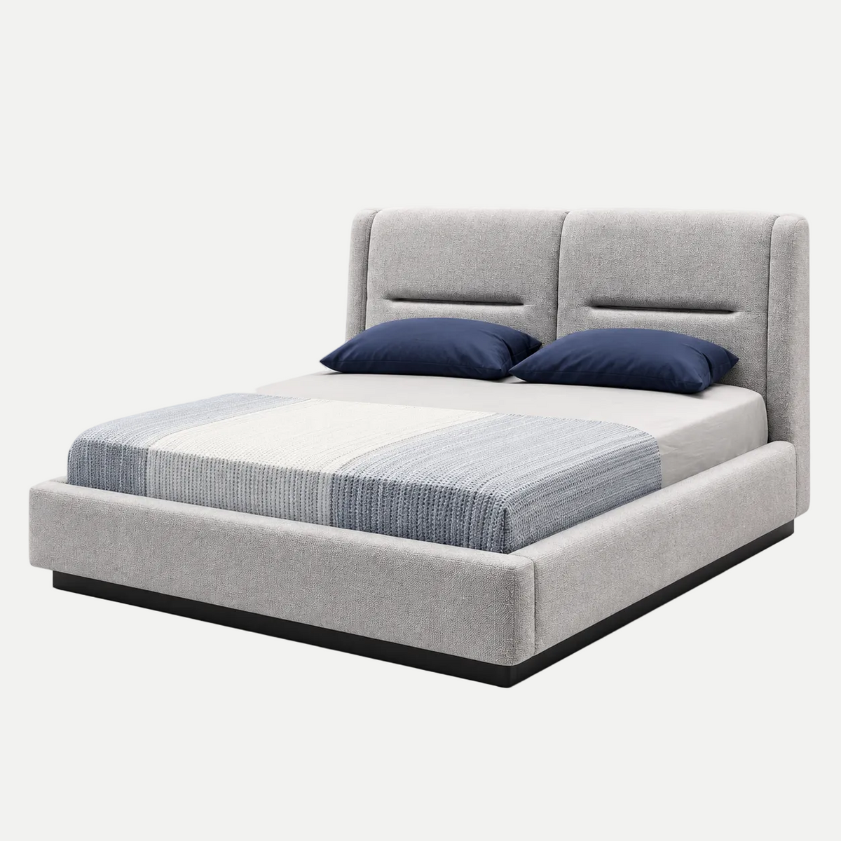 A modern platform bed with a light gray upholstered headboard and base, styled with a striped blue and white comforter and two navy blue pillows, set against a plain white background.