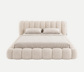 A modern platform bed with a high, vertically channel-tufted headboard and a matching padded footboard, upholstered in a textured light beige fabric. The bed is dressed in matching beige bedding, including two pillows, and is photographed against a seamless white background.