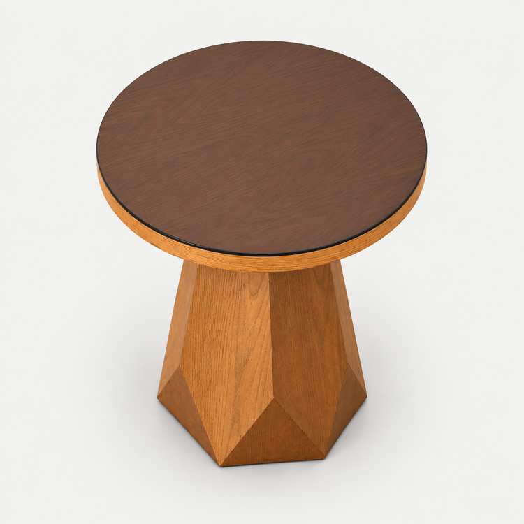 A modern side table with a round dark brown wood top and a faceted geometric pedestal base in a warm medium brown wood finish, shown on a light gray background.