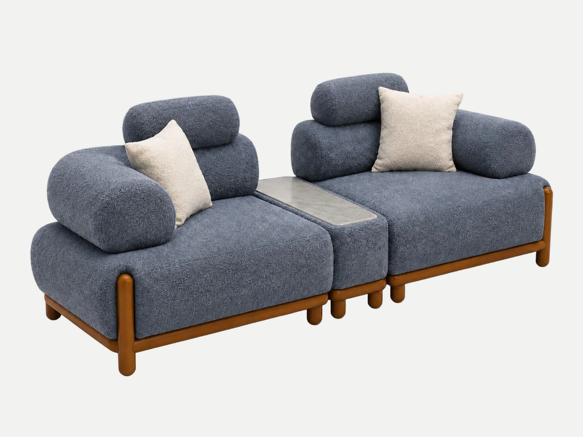 A modern two-seater sofa with textured blue-gray fabric upholstery, light wood legs, and two cream throw pillows, shown on a plain white background.