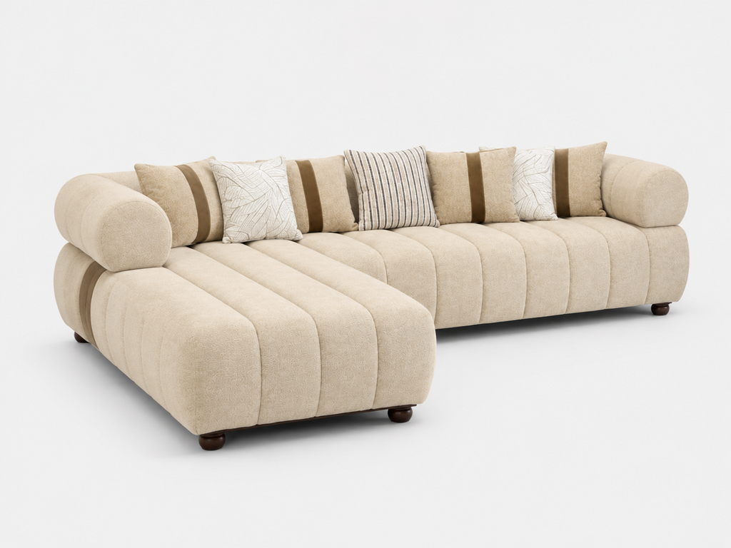 A modern curved sectional sofa in a light beige textured fabric, featuring a chaise lounge on the left, tufted channel stitching, and multiple decorative throw pillows in beige, white, and brown, set against a plain light gray background.