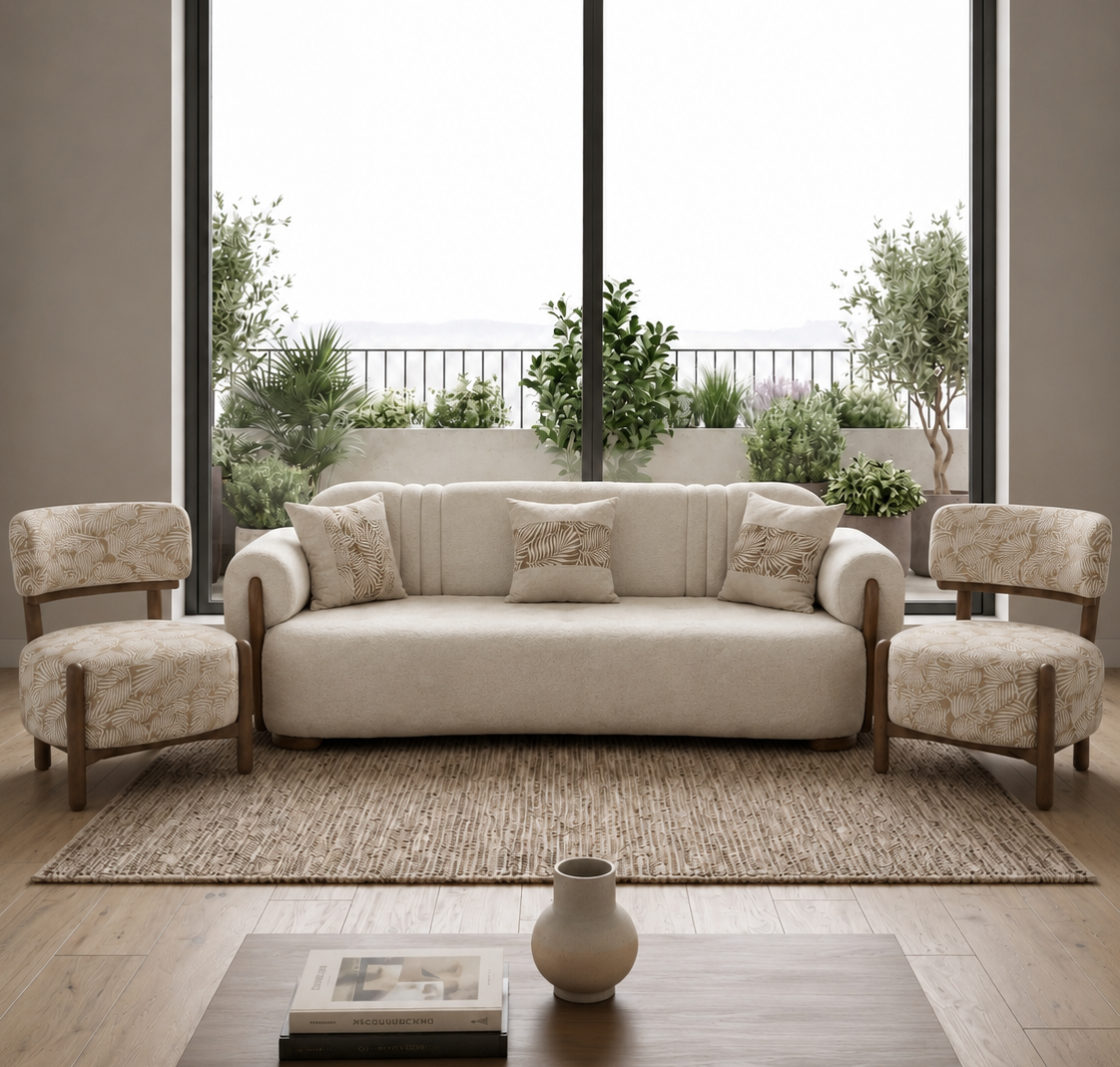 A modern living room setup featuring a cream-colored three-seater sofa flanked by two matching armchairs with a floral pattern, all arranged on a woven area rug in front of a large black-framed window.