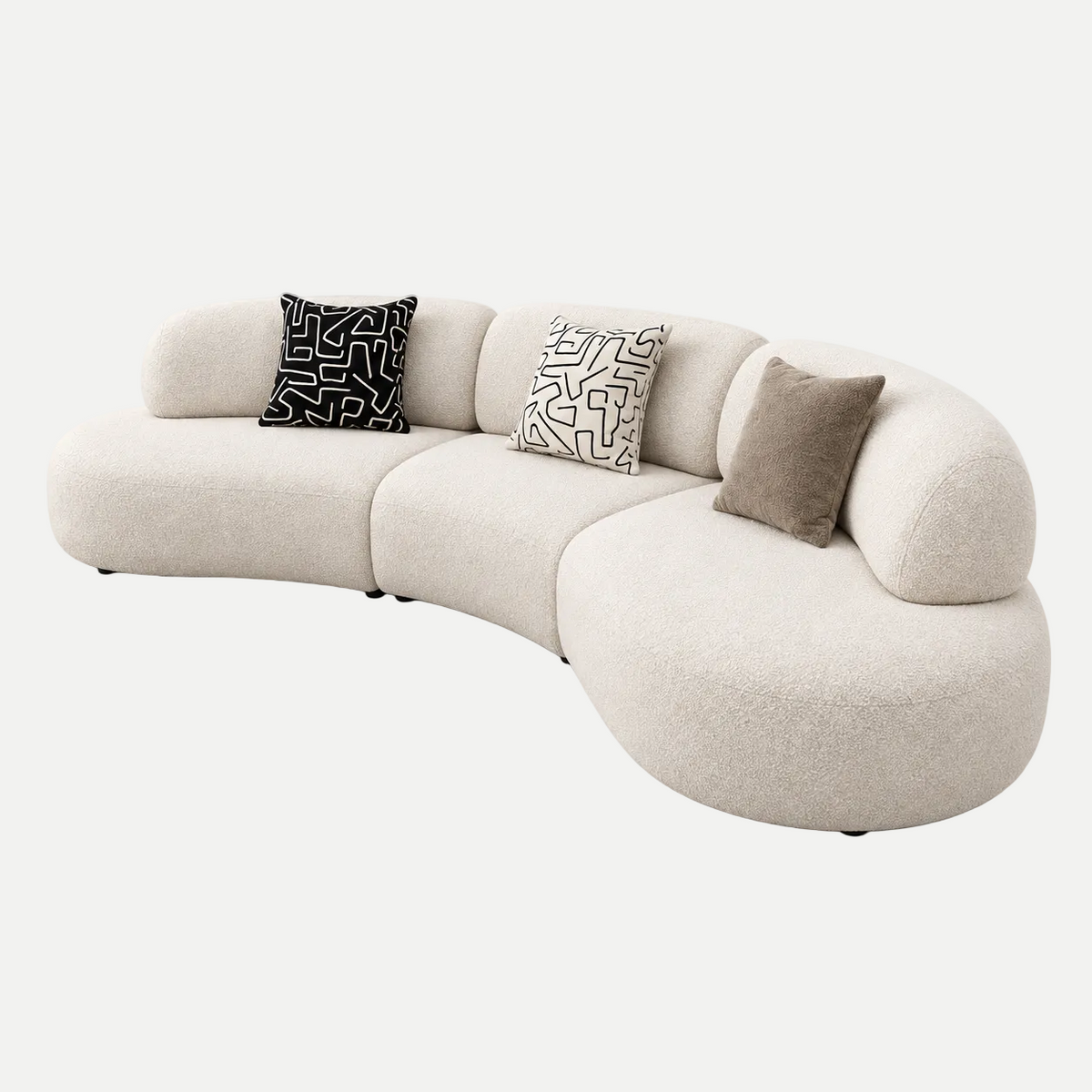 A curved modular upholstered sofa in a warm off-white bouclé fabric, styled with three decorative throw pillows on a seamless light gray background.