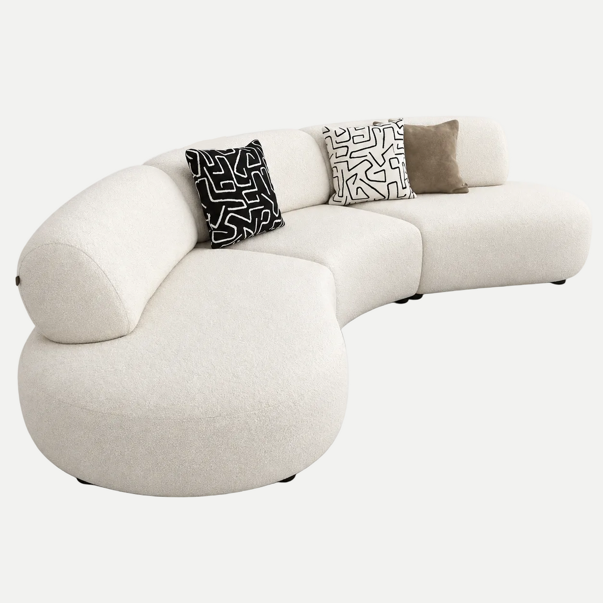A modern curved modular sofa upholstered in cream bouclé fabric, styled with three decorative throw pillows on a seamless white studio background.