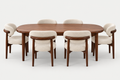A mid-century modern dining set featuring a rounded rectangular wooden table and six matching upholstered chairs with curved backs and cream fabric, shown on a light gray background.