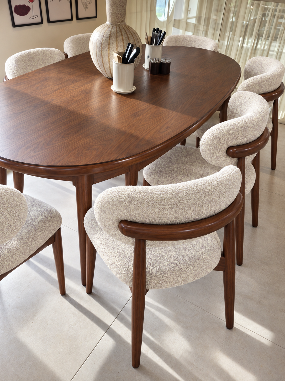 An oval wooden dining table with a warm medium-brown finish, surrounded by upholstered dining chairs in a light cream bouclé fabric with matching brown wooden frames, set in a bright, modern dining room.
