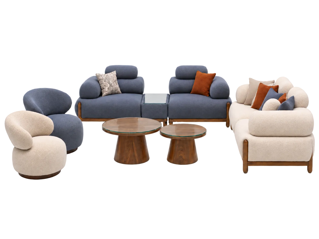 A mid-century modern furniture set featuring a blue modular sofa, a cream curved armchair, a matching cream sofa, two wooden coffee tables, and accent pillows, displayed on a light gray background.