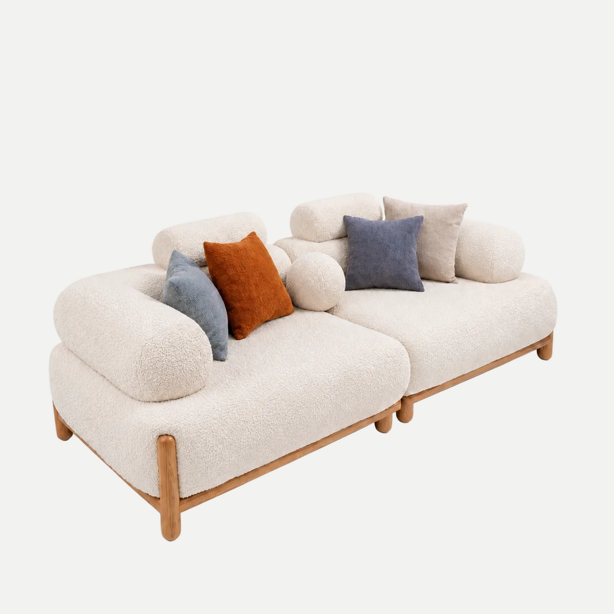 A modern two-seater sofa upholstered in cream bouclé fabric with light natural wood legs and trim, styled with several decorative throw pillows in blue, rust orange, and beige on a plain white background.