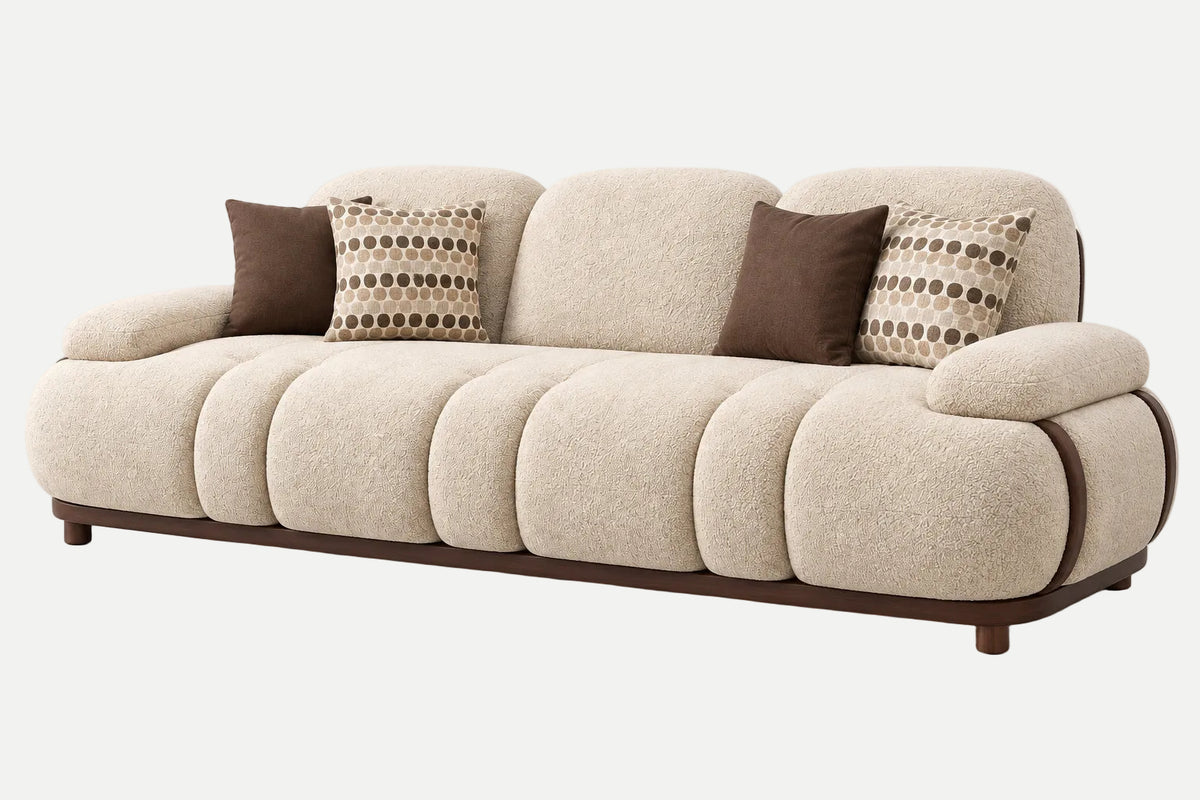 A modern three-seater sofa upholstered in a textured cream bouclé fabric with dark brown wooden legs and trim, styled with four throw pillows including two solid brown and two patterned beige and brown.
