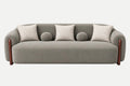 A modern gray upholstered sofa with rounded arms, dark wood legs, four textured light beige throw pillows, and two round matching gray pillows, shown on a clean white background.