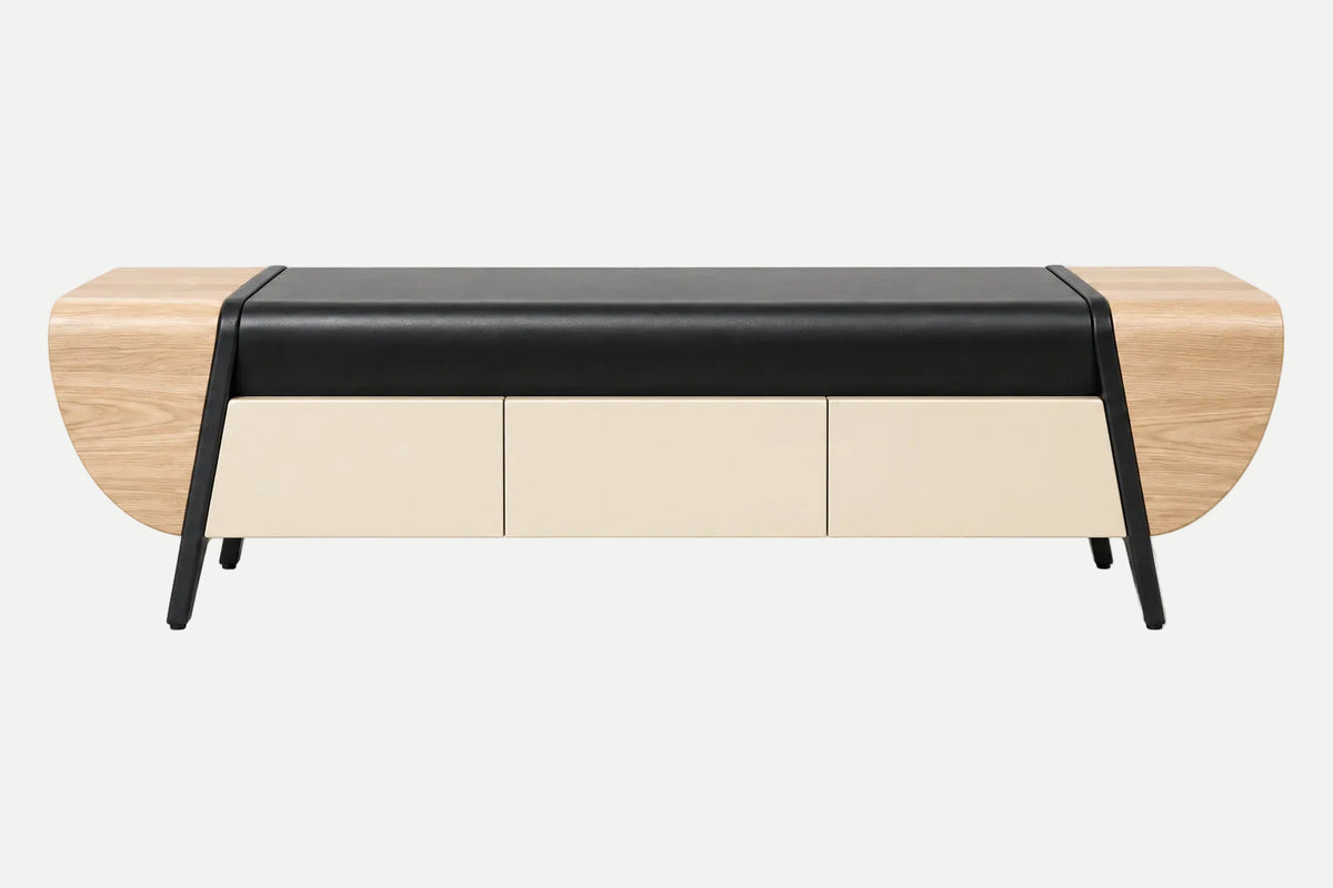 A modern sideboard or bench with a black leather top, cream-colored front panels, and light wood side panels, supported by slim black metal legs, shown against a plain light gray background.